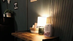 Una mesa de madera con sillas, una lámpara y un electrodoméstico blanco en la pared.