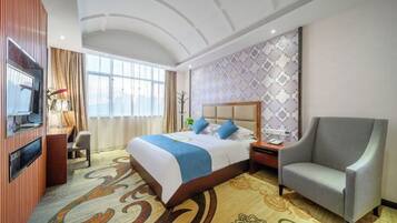 A hotel room with a bed, a TV, a chair, a desk, and a window.