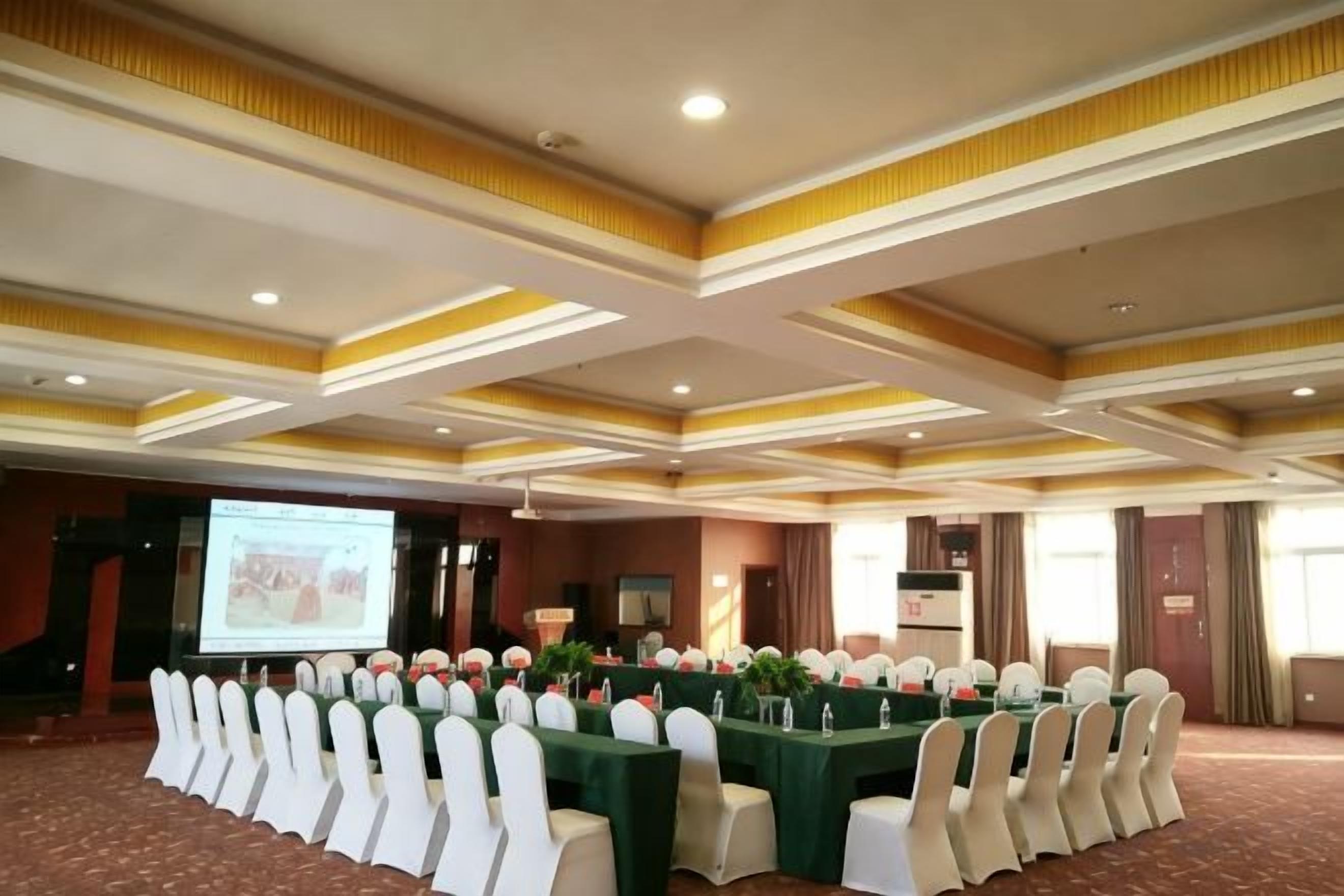 A conference room with a long table, chairs, and a projector screen.