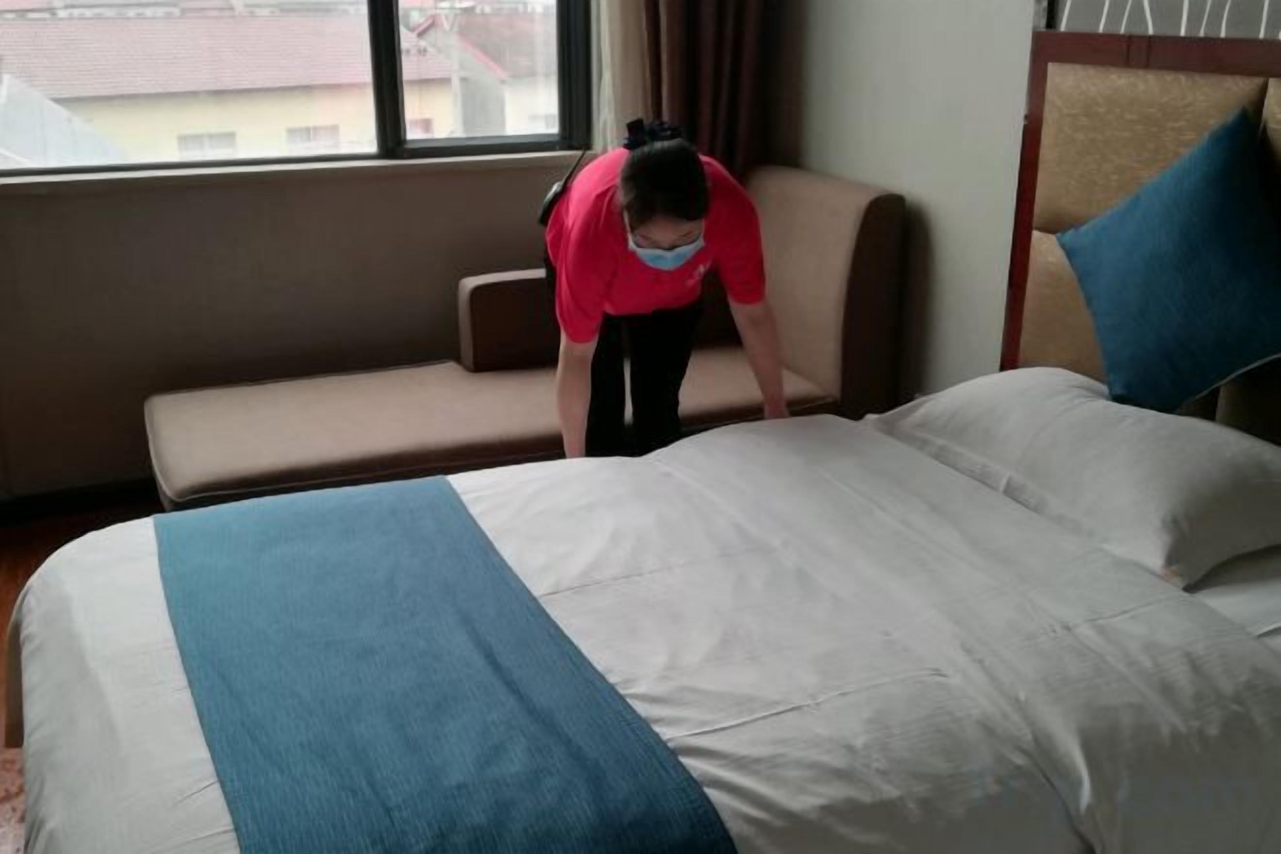 A hotel room with a bed, a sofa, and a window.