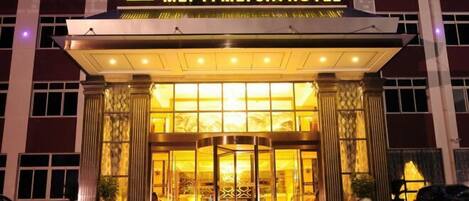 The exterior of MEI YI MEI JIA HOTEL with a prominent entrance, large glass doors, and a well-lit facade.