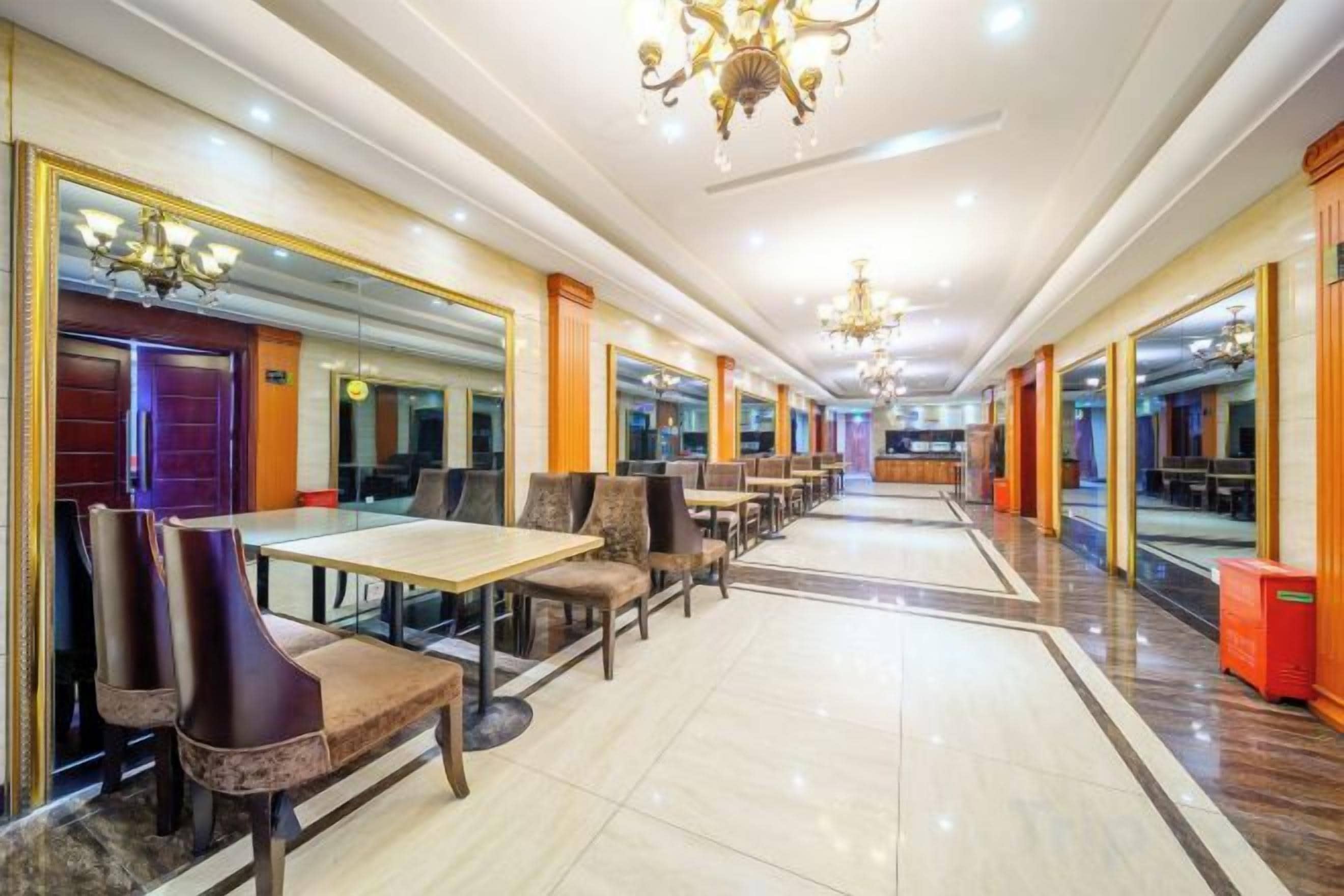 A hotel lobby with a long corridor, mirrored walls, and a chandelier.