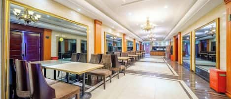 Un vestíbulo de hotel con un largo pasillo, paredes espejadas y un candelabro.