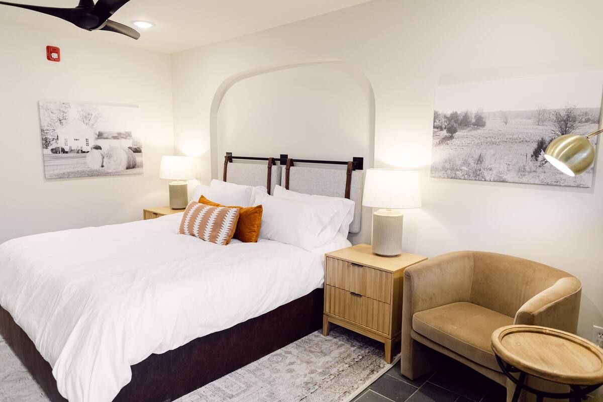 A neatly arranged bedroom with a bed, bedside tables, a chair, and two wall-mounted lamps.