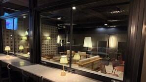 Un interior moderno con una zona de bar, asientos y una cocina visible al fondo.