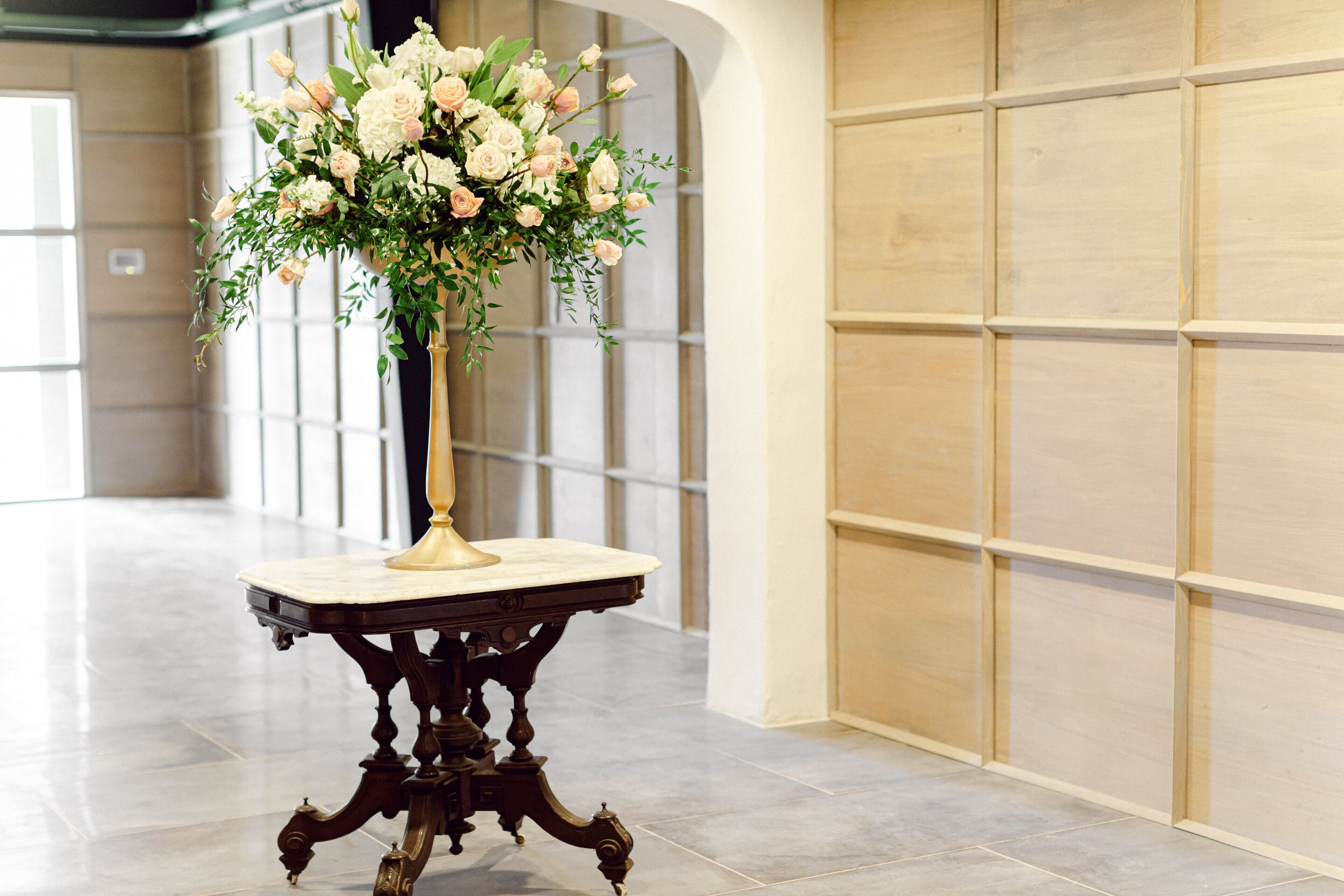 Un pasillo con una mesa de mármol y un arreglo floral.