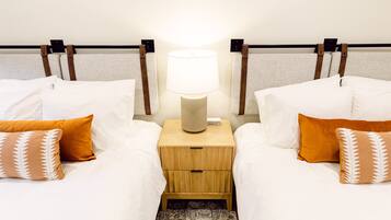 A hotel room with two beds, a nightstand with a lamp, and a patterned rug.