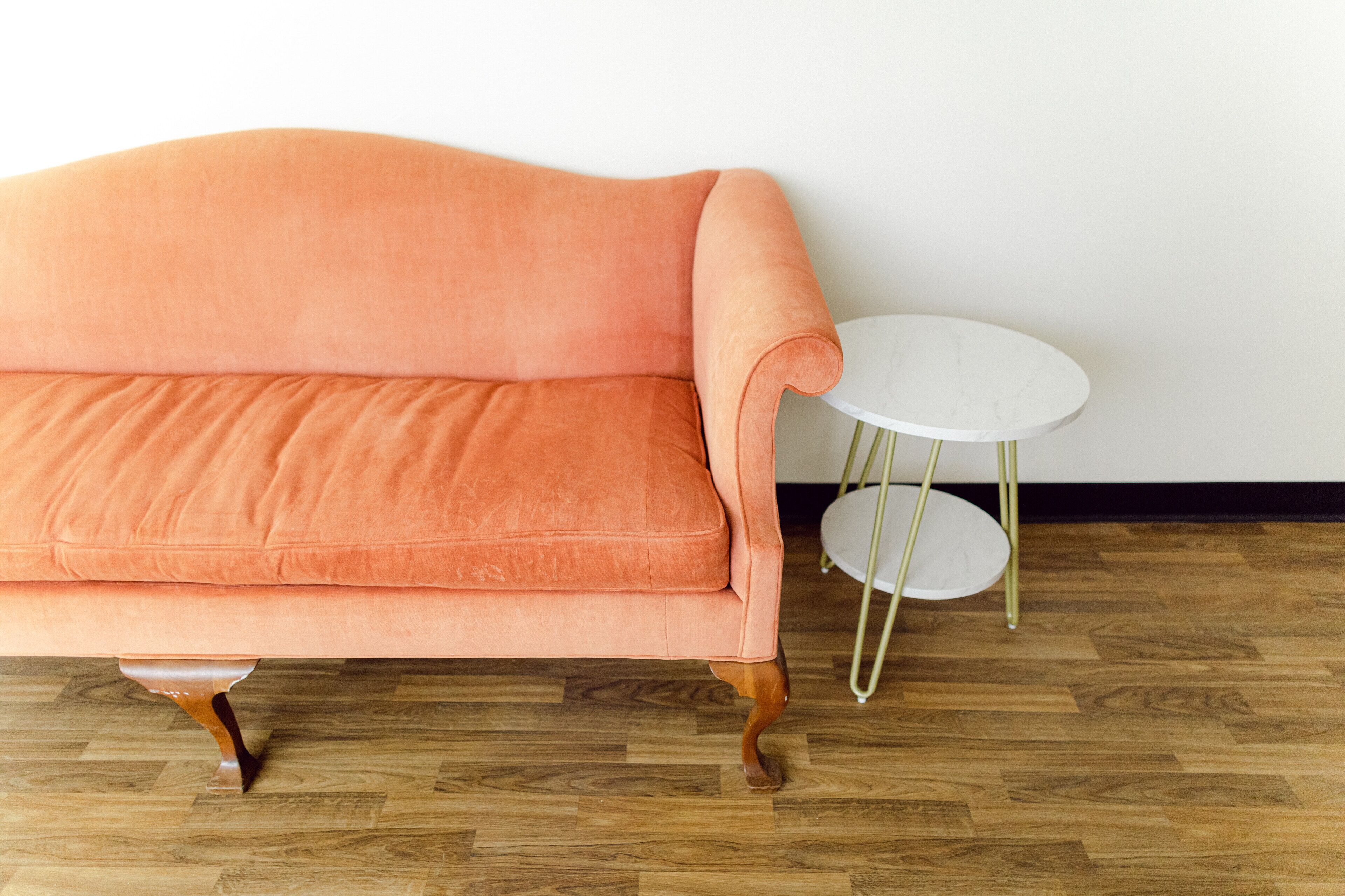 A room with a peach-colored sofa and a small white table with gold legs.