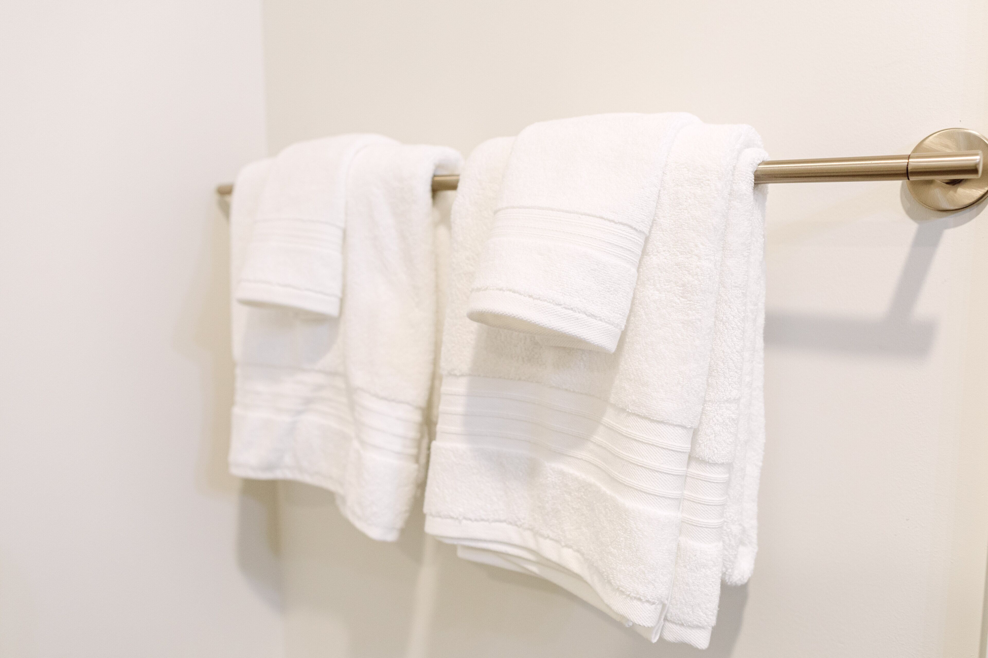 Une salle de bain avec deux serviettes blanches suspendues à une barre à serviettes.