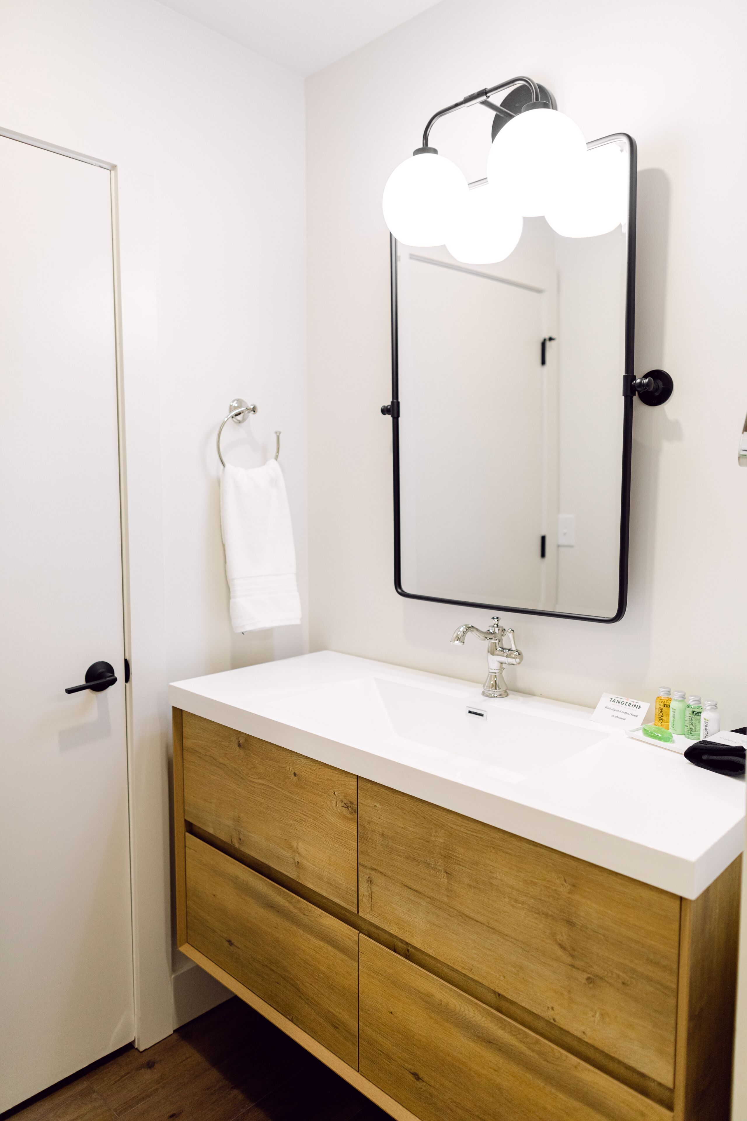A bathroom with a white sink, wooden vanity, and a mirror with cloud-shaped lights.