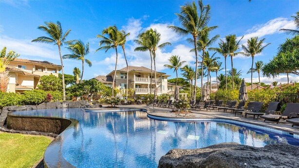 Ein Resort mit großem Pool, Palmen und einem Gebäude mit Balkonen.