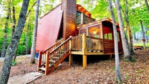 Een chalet met een houten terras en een trap naar een balkon.
