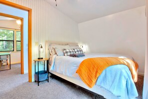 A bedroom with a bed, bedside table, and a view of the outdoors.