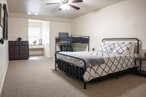 Une chambre à coucher avec un lit superposé, une commode et un ventilateur de plafond.