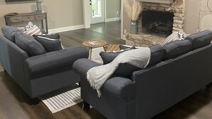Una sala de estar con chimenea de piedra, un ventilador de techo y un televisor de pantalla plana montado en la pared.