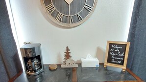 A wooden cabinet with a clock above it, a small tree model, a tissue box, and a welcome sign. - Bear Mountain Branson Suite Overlooking Pointe Royale Golf Course in Branson! (Branson)