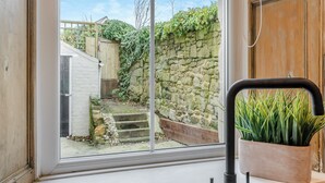 A window with a view of a stone wall and a wooden door.