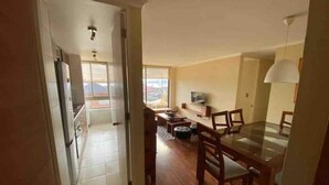 A dining area with a wooden table and chairs, a television on the wall, and a window providing natural light. - Beautiful 2D/2B apartment with pool, barbecue area and AAVV/ (Los Angeles)