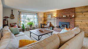 Una sala de estar con sofá, sillones, una mesa de centro, chimenea y vistas al exterior.