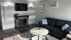Un salon moderne avec une cheminée en pierre, un canapé gris foncé et une table basse ronde.