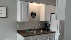 Une cuisine moderne avec des meubles blancs, un plan de travail en granit et un panneau décoratif en forme de cœur accroché au mur.