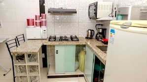 Een kleine keuken met een gasfornuis, een magnetron en een koelkast.