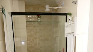 Een badkamer met een douche in een glazen cabine, een wit toilet en een granieten aanrechtblad.