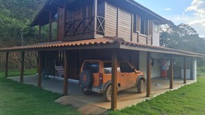 Ein zweistöckiges Holzhaus mit einer Veranda und einem geparkten SUV.