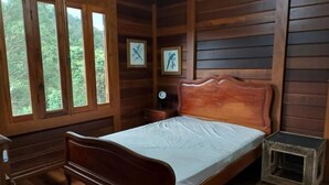 Ein Schlafzimmer einer Holzhütte mit Bett, Nachttisch, einer Uhr und gerahmten Bildern an der Wand.