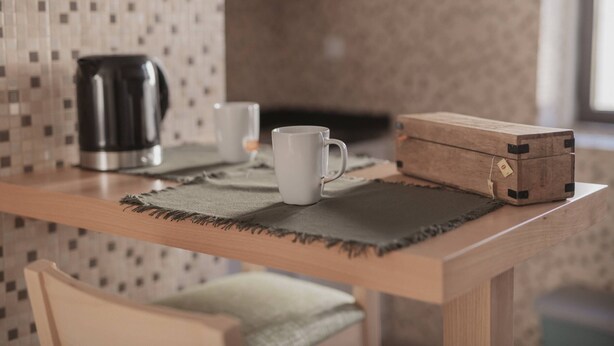 A wooden table with a white mug, a black coffee pot, and a wooden box with a tag. - Albina's Guest House (Leça da Palmeira)