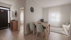 A modern living room with a dining area, a sofa, a coffee table, and a clock on the wall. - Albina's Guest House (Leça da Palmeira)