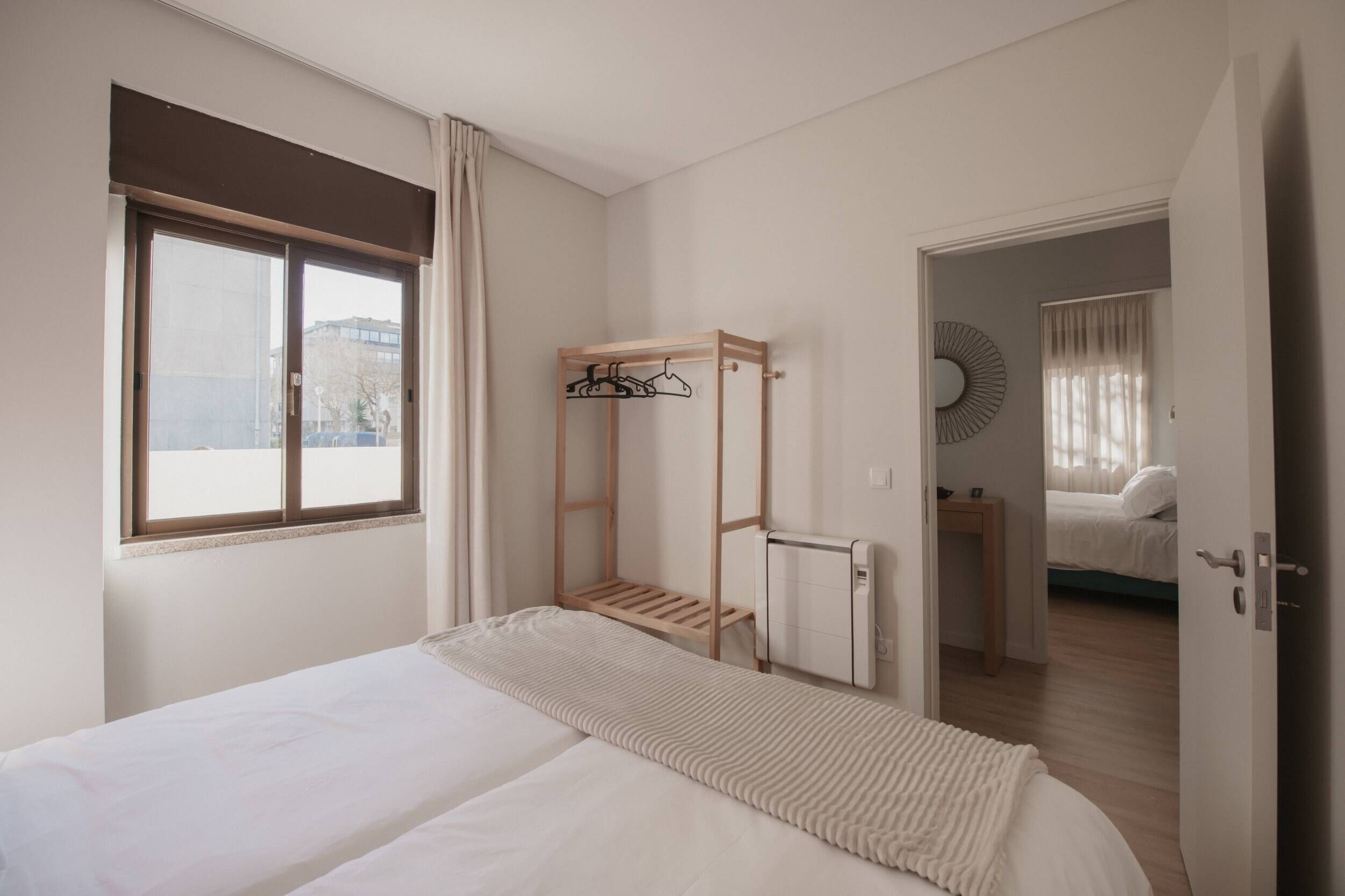 A bedroom with a bed, a wooden shelf, a radiator, and a view through an open door.