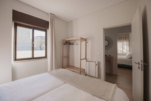 Een slaapkamer met een bed, een houten plank, een radiator en een uitzicht door een geopende deur.