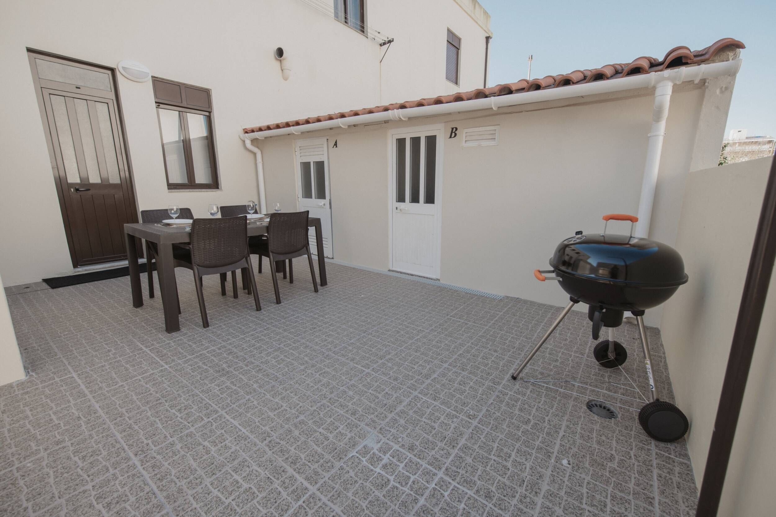 A patio area with a table and chairs, a barbecue grill, and a door labeled 'A'.