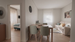 A modern living room with a dining area, a sofa, and a bed in the background. - Albina's Guest House (Leça da Palmeira)