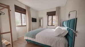 A bedroom with a bed, a wooden ladder, a mirror, and a window with curtains. - Albina's Guest House (Leça da Palmeira)