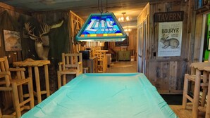 A room with a covered pool table, wooden furniture, and a sign for 'Zite Beer'.