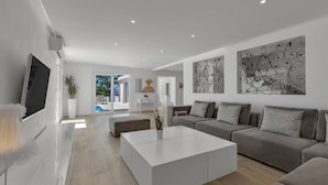 A modern living room with a large white coffee table, grey sofas, and a flat-screen TV mounted on the wall. - Villa Simply White with Pool (Makarska)
