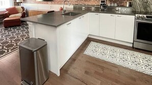 A modern kitchen with a brick wall, stainless steel appliances, and a large island.