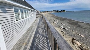 Un muelle de madera que lleva a una playa con un edificio blanco a la izquierda.