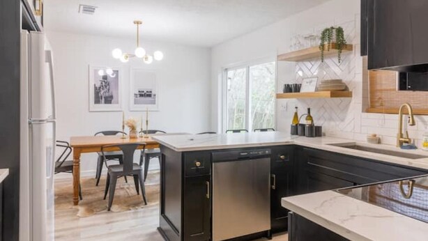 Une cuisine moderne dotée d’un îlot central, d’un lave-vaisselle encastré et d’un coin repas avec une table et des chaises.