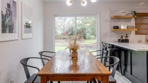 Une cuisine moderne avec une table à manger en bois, des chaises noires et un luminaire suspendu.