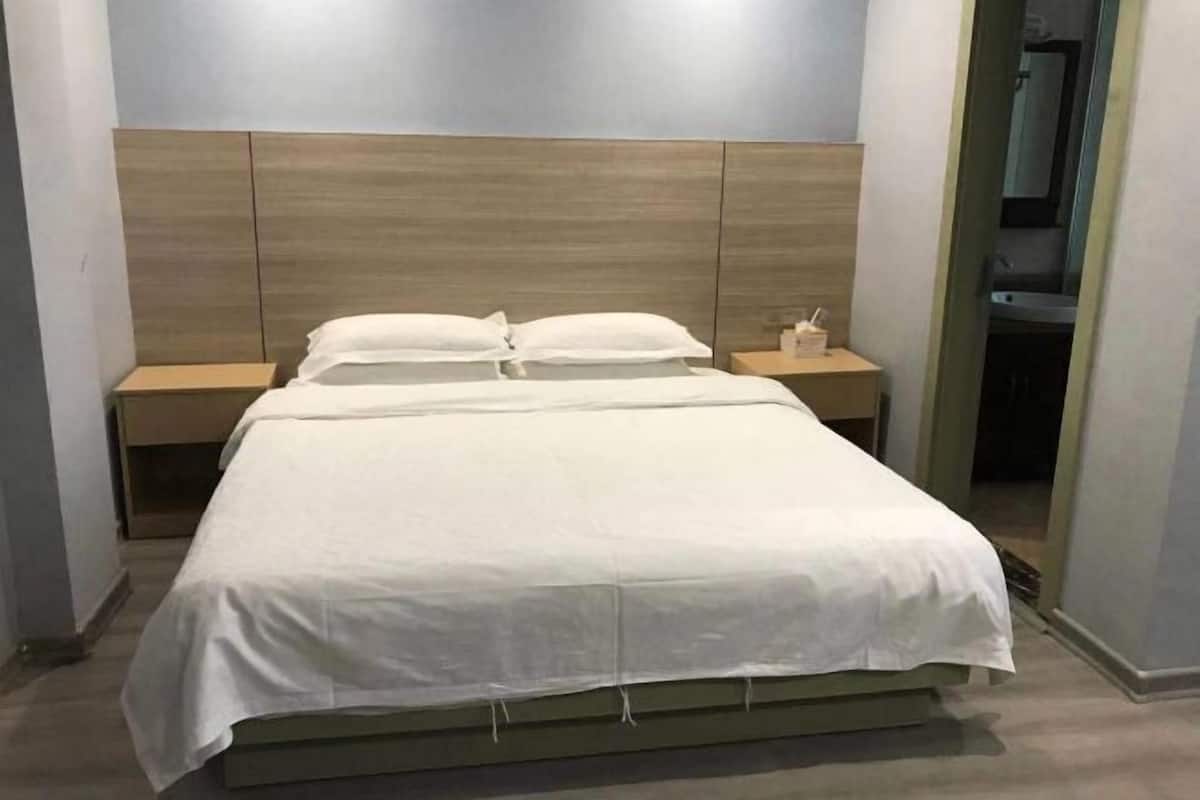 A neatly made bed with a wooden headboard, two bedside tables, and a mirror on the wall.