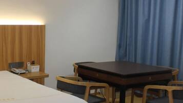 Habitación de hotel con cama, mesita de noche, lámpara y una pequeña mesa con sillas.