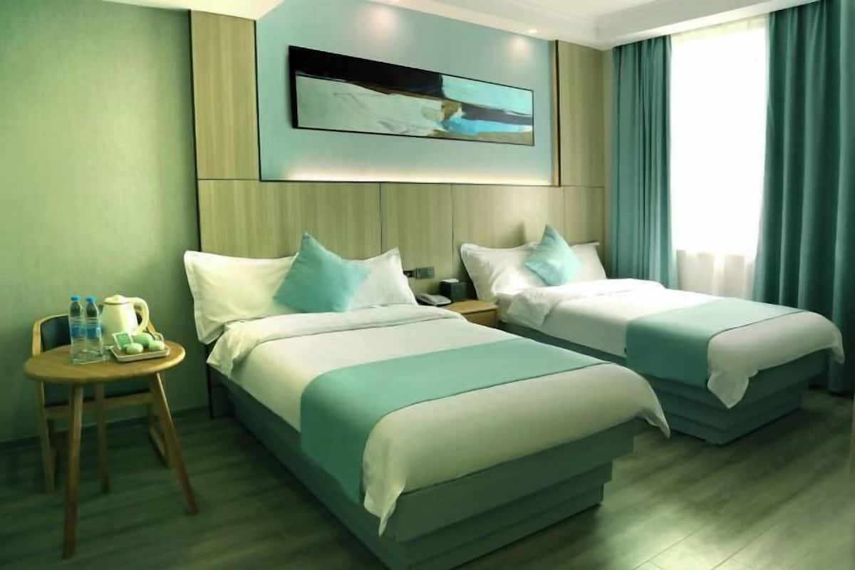 A hotel room with two beds, a small table with toiletries, and a painting on the wall.
