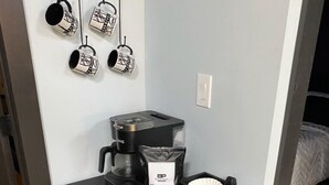 A compact kitchenette with a coffee maker, a coffee bag, and a coffee bar.