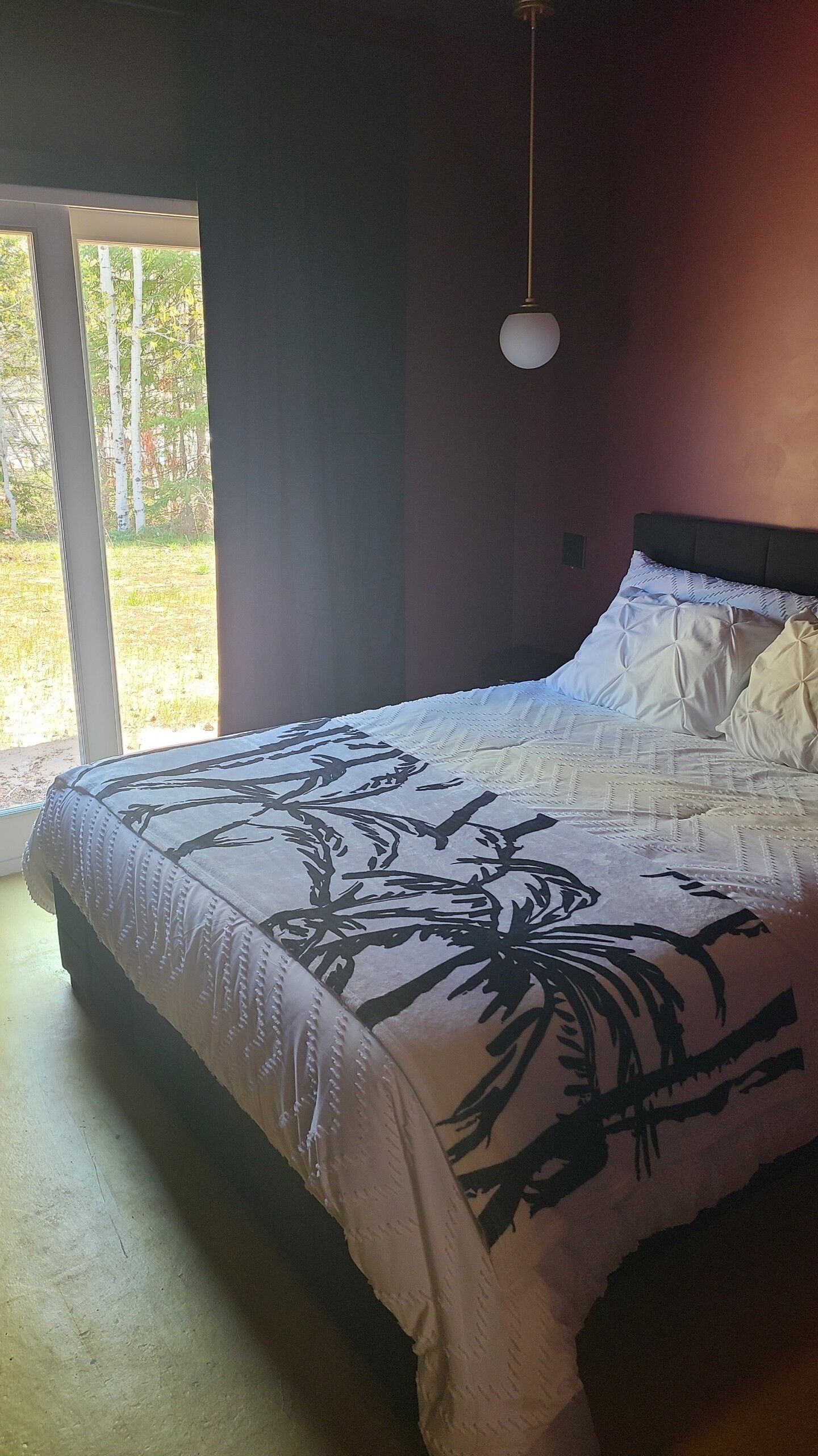 Un dormitorio con cama, ventana y lámpara colgante.