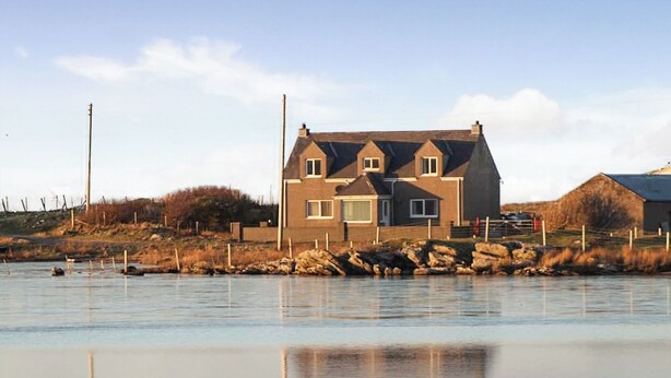 Een huis aan een rustig water met een heldere lucht.