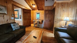 A cozy wooden interior with a sofa, a coffee table, and a lamp.