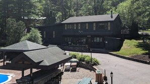 A lodge with a large deck area, a pool, and a well-maintained lawn.